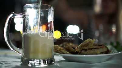 Pouring beer with foam into glass mug