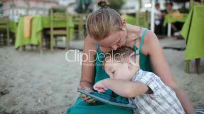 Mother and son using tablet PC near beach cafe