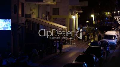 People walking along narrow street in Greece at night