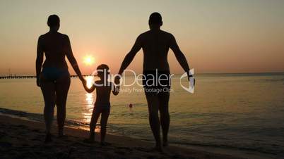 Parents and child bathing in the sea at sunset