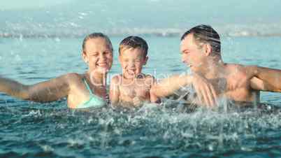 Family of three splashing water in sea