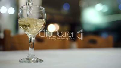 Pouring white wine into glass in restaurant