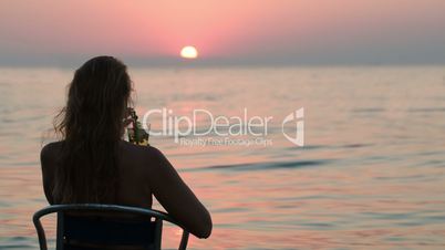 Woman with cocktail enjoying sunset on the shore