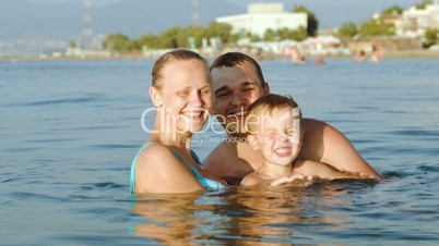 Happy parents and son bathing in sea on resort