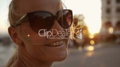 Smiling woman in sunglasses outdoor during sunset