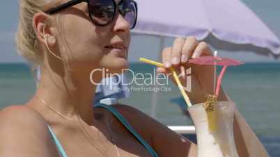 Woman with cocktail sunbathing on beach