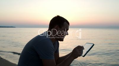 Man using tablet computer on the beach