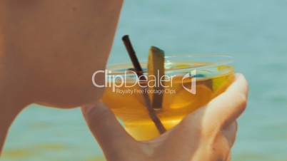 Woman drinking refreshing cocktail with a straw