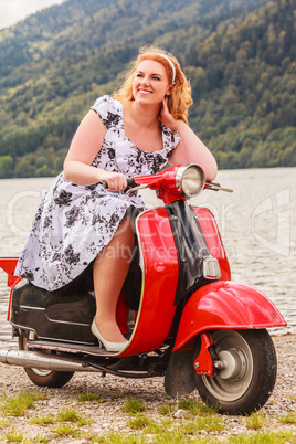 Rothaarige Schönheit mit Übergewicht auf einem roten Motorroller
