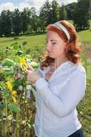 Übergewichtige rothaarige Frau auf einem Sonnenblumenfeld.