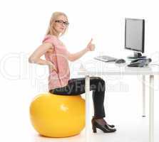 Geschäftsfrau sitzt auf einem Sitzball am Schreibtisch