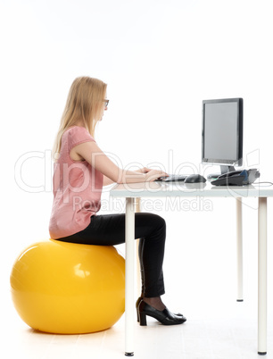 Geschäftsfrau mit Sitzball am Schreibtisch