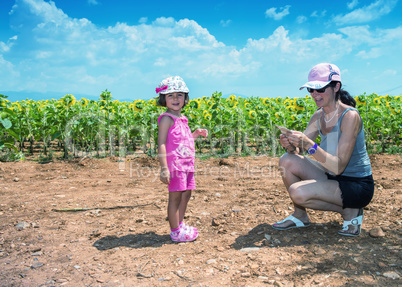 Mother and daughter enjoying outdoor with sunflowers field