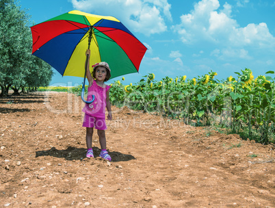 Baby girl enjoying outdoor with colorful umbrella and sunflowers