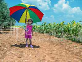 Baby girl enjoying outdoor with colorful umbrella and sunflowers