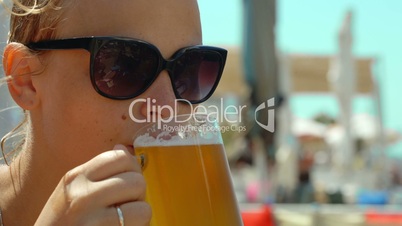 Young woman drinking cold beer on a hot day