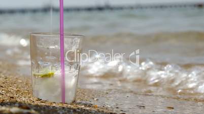 Pouring fizzy drink into glass on the sand