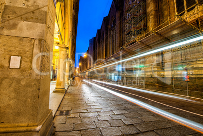 Illuminated street of Bologna at night with bus light trails