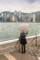 Asian girl with umbrella mesmerized by Hong Kong panorama
