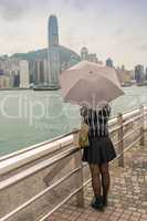 Asian girl with umbrella mesmerized by Hong Kong panorama