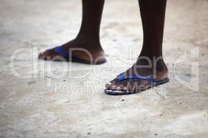 Feet of an African man in blue flip flops
