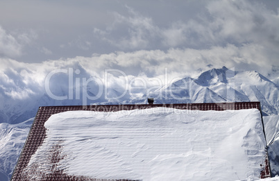 Snowy roof and mountains in clouds