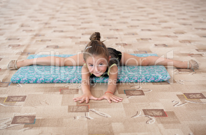 Little girl doing leg-split on the floor