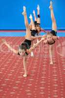 Young female gymnasts doing vertical leg-split
