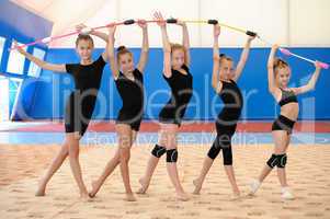 Young female gymnasts making bow with Indian clubs