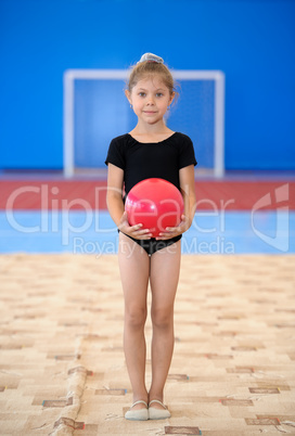 Little gymnast girl with red ball