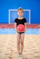 Little gymnast girl with red ball