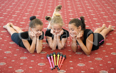 Three girls on the floor looking at Indian clubs