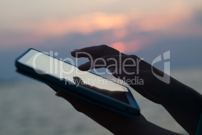 Woman hands typing on pad outdoor at sunset