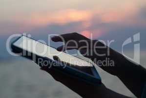 Woman hands typing on pad outdoor at sunset