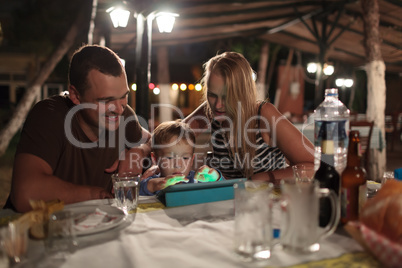 Parents and child with tablet PC in outdoor cafe