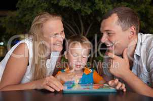 Happy family with tablet PC outdoor in the evening