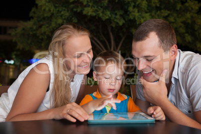 Family of three with pad in outdoor cafe