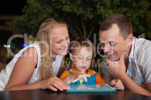 Family of three with pad in outdoor cafe
