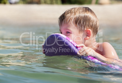 Little boy swimming on board near the beach