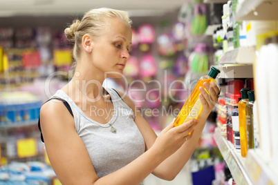Woman looking at shampoo bottle in the store