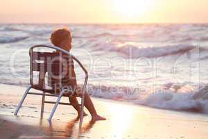 Boy sitting on the chair by sea