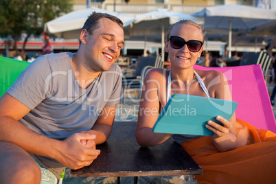 Man and woman with pad on the beach