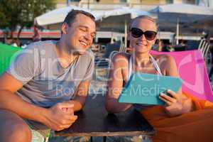 Man and woman with pad on the beach