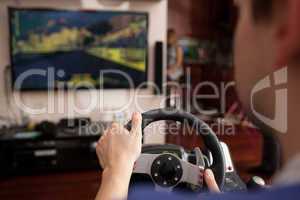 Man playing racing game with steering wheel simulator