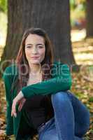 Woman sitting in the autumn before the tree trunk