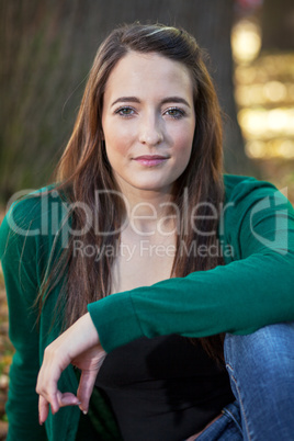 Woman sitting in the autumn before the tree trunk