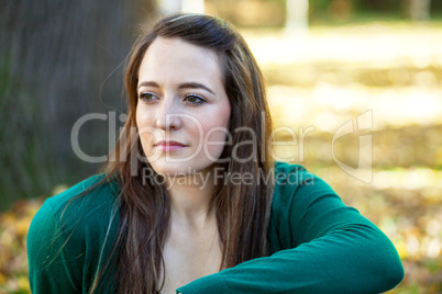 Woman sitting in the autumn before the tree trunk