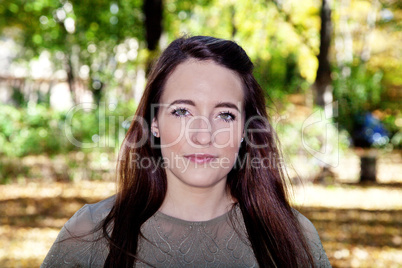 Woman with long hair in front of colorful trees in autumn