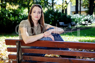 Woman sitting on park bench in autumn