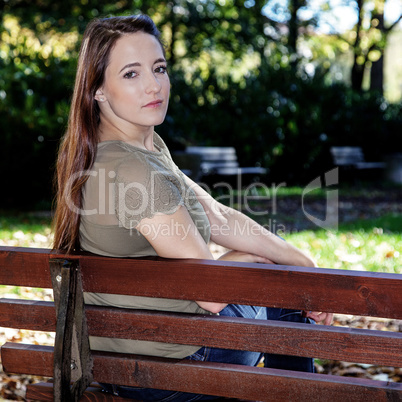 Woman sitting on park bench in autumn